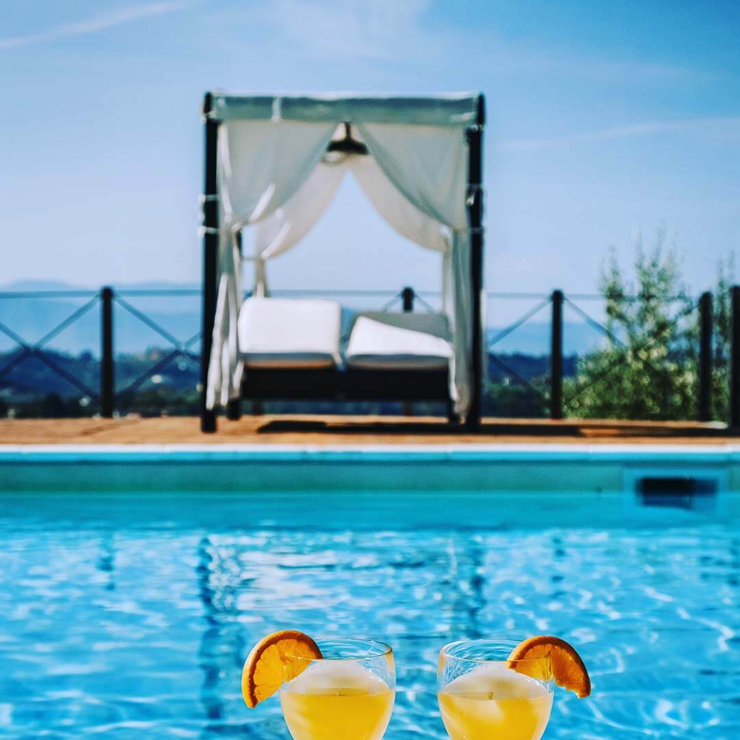 Two cocktails by the side of a crystal clear swimming pool