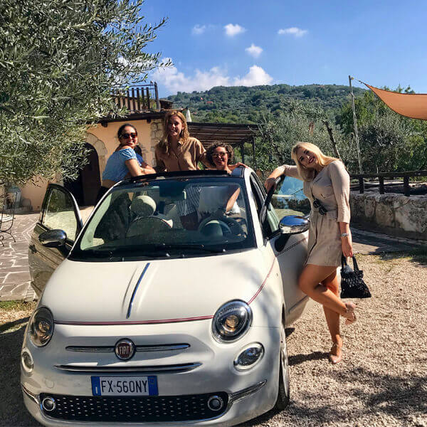 A Group Of People Standing Next To A Fiat 500 Car